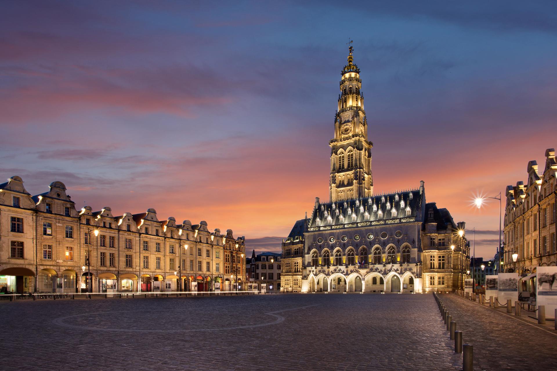 Place des Héros d'Arras illuminée au crépuscule avec son beffroi gothique et ses façades baroques flamandes